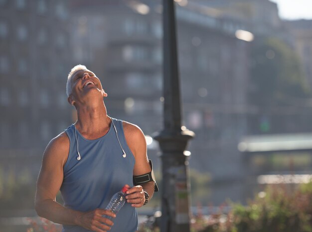 Porträt eines gutaussehenden Senior-Jogging-Mannes, während er sich entspannt und nach dem morgendlichen Lauf eine Pause einlegt