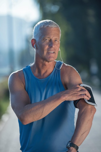 Porträt eines gutaussehenden Senior-Jogging-Mannes, während er sich entspannt und nach dem morgendlichen Lauf eine Pause einlegt