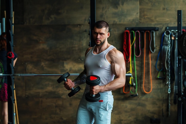 Porträt eines gutaussehenden sportlichen Mannes mit muskulösem Körper beim Gewichtheben im Fitness-Studio