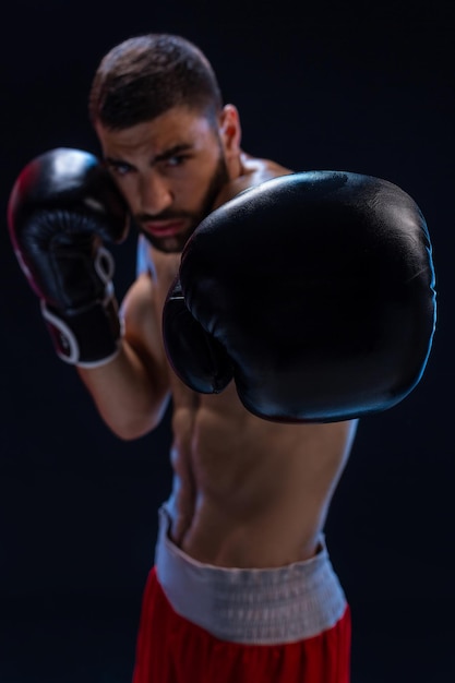 Porträt eines harten männlichen Boxers, der in Boxhaltung vor schwarzem Hintergrund posiert