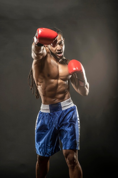 Porträt eines hemdlosen Boxers, der gegen schwarzen Hintergrund schlägt
