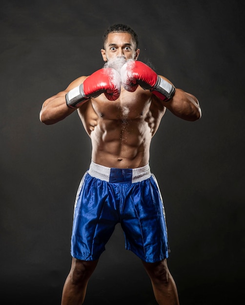 Porträt eines Hemdlosen Boxers, der vor schwarzem Hintergrund steht