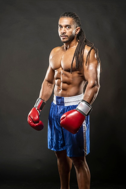 Porträt eines hemdlosen Boxers, der vor schwarzem Hintergrund steht