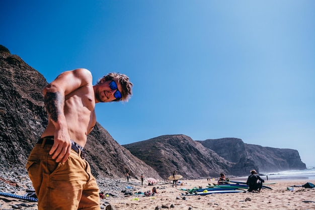 Porträt eines hemdlosen jungen Mannes, der am Strand steht