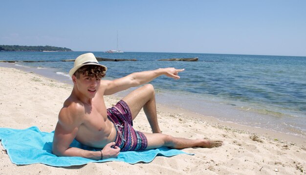 Foto porträt eines hemdlosen mannes, der gegen den klaren himmel am strand entspannt.