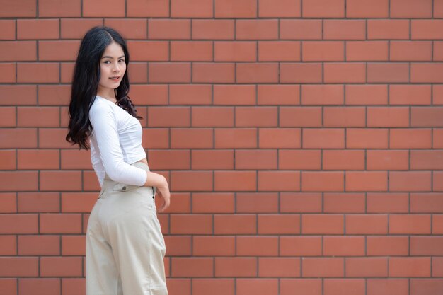 Porträt eines Hipster-Mädchens auf Backsteinmauerhintergrund Schöne asiatische Frau posiert für ein Foto im Kawaii-Stil