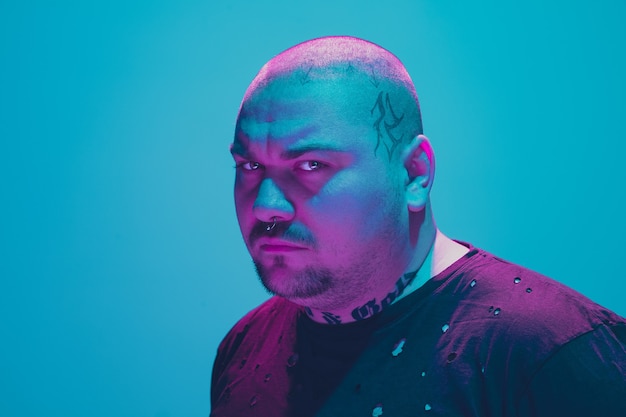 Porträt eines Hipster-Typs mit buntem Neonlicht auf blauem Hintergrund