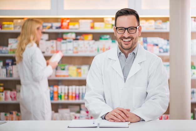 Porträt eines hübschen Apothekers am Zähler einer Drogerie, weibliche Kollegefunktion