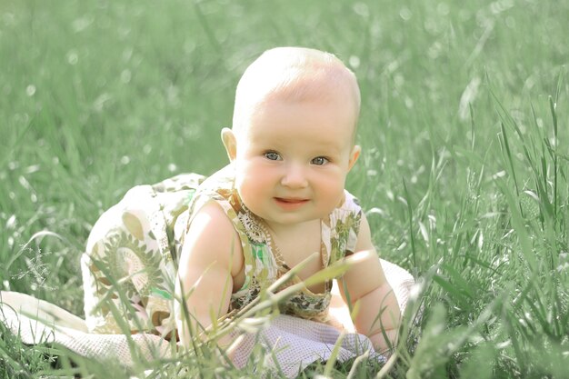 Porträt eines hübschen Babys auf dem Rasen an einem Sommertag