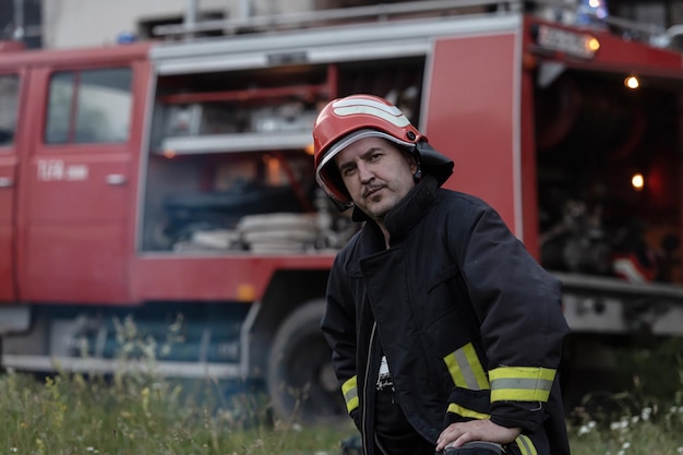 Porträt eines hübschen, depressiven und müden Feuerwehrmanns in der Nähe eines Feuerwehrautos. Foto in hoher Qualität