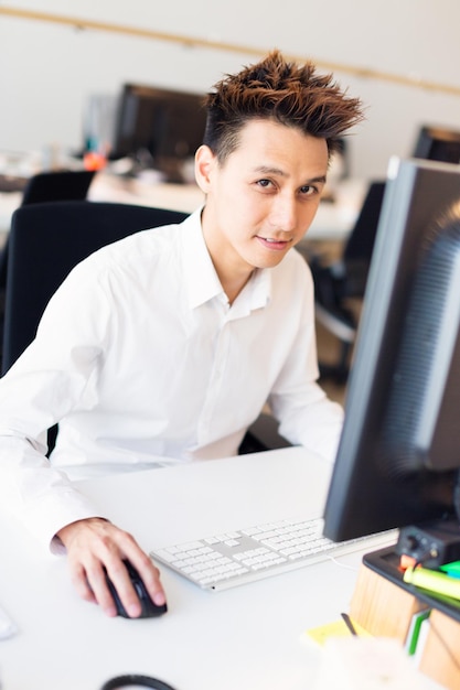 Foto porträt eines hübschen geschäftsmanns, der im büro am computer arbeitet