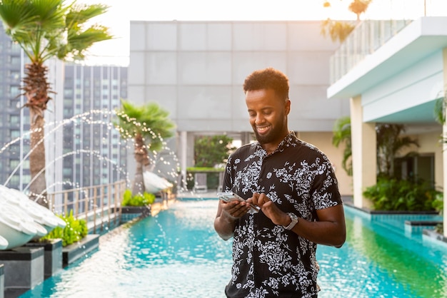 Porträt eines hübschen jungen afrikanischen Mannes im Freien mit Handy