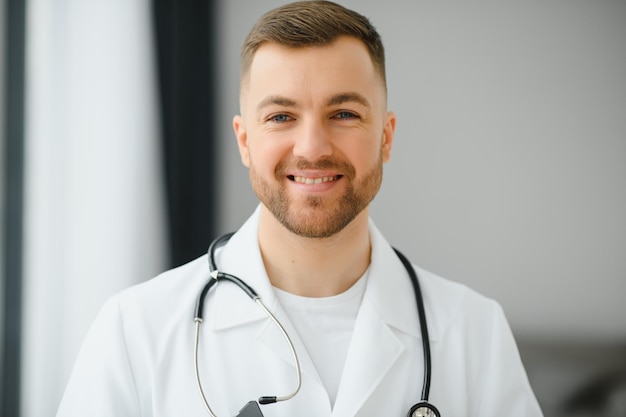 Porträt eines hübschen jungen Arztes auf einem Krankenhausflur, der lächelnd in die Kamera schaut.