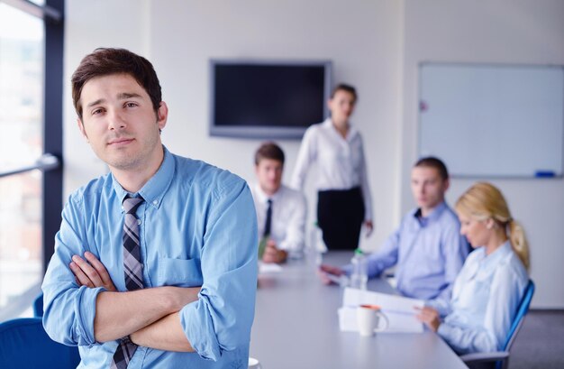 Porträt eines hübschen jungen Geschäftsmannes bei einem Treffen im Büro mit Kollegen im Hintergrund