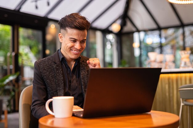 Porträt eines hübschen jungen Geschäftsmannes mit Laptop im Café