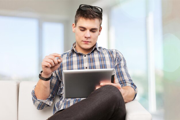 Porträt eines hübschen jungen glücklichen Mannes, der digitales Tablet verwendet