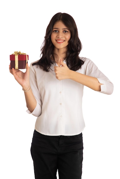 Porträt eines hübschen jungen Mädchens, das mit Geschenkbox auf weißem Hintergrund hält und posiert