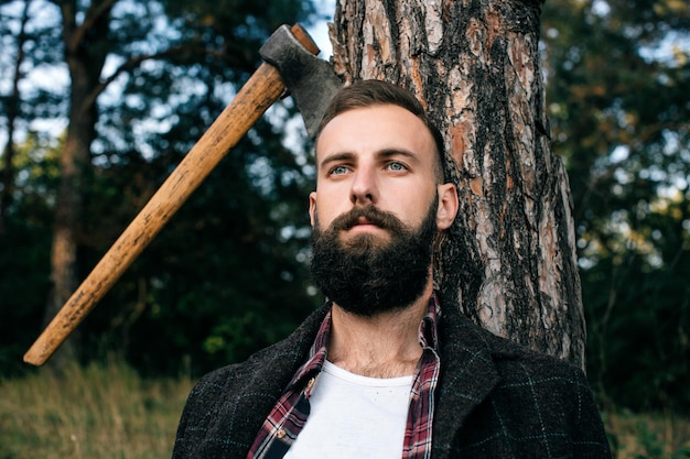 Porträt eines hübschen jungen Mannes im Wald, der als Holzfäller arbeitet