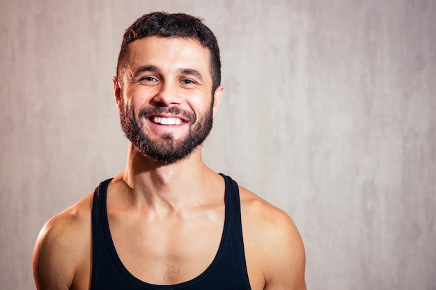 Porträt eines hübschen jungen Mannes in einem schwarzen T-Shirt auf grauem Hintergrund. Sportler lächelt und flirtet