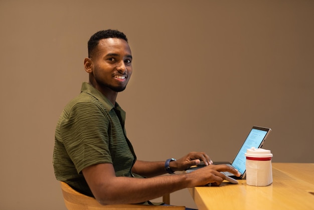 Porträt eines hübschen jungen schwarzen Mannes mit Laptop-Computer im Café