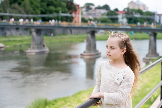 Porträt eines hübschen kleinen glücklichen Prinzessinnenmädchens mit langen blonden lockigen Haaren am sonnigen Sommertag