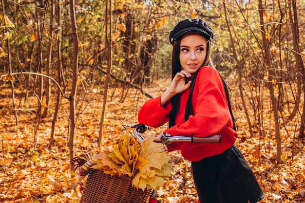 Porträt eines hübschen Mädchens mit einem roten Fahrrad im Herbstwald