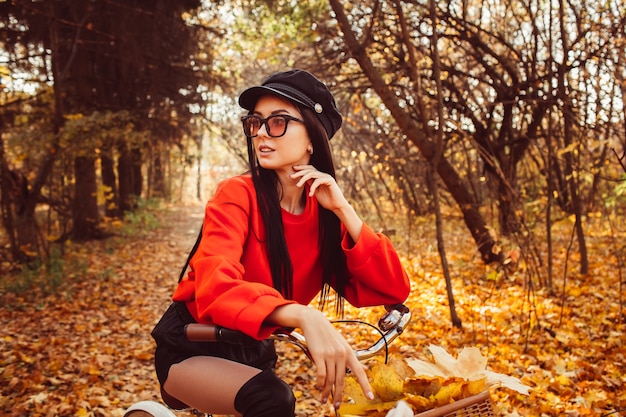 Porträt eines hübschen Mädchens mit einem roten Fahrrad im Herbstwald