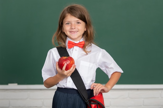 Porträt eines hübschen Mädchens mit rotem Apfel im Unterrichtslernen und Kinderkonzept