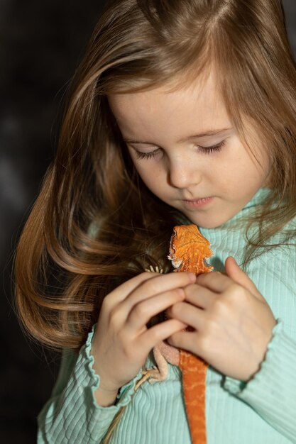 Porträt eines hübschen Mädchens mit rotem bärtigen Agama-Leguan auf grauem Hintergrund Kleines Kind