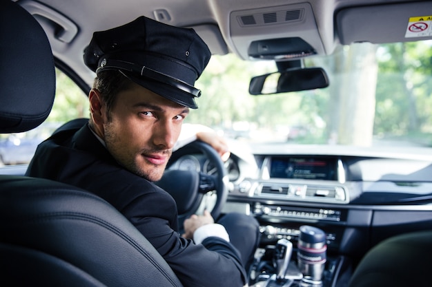 Foto porträt eines hübschen männlichen chauffeurs, der in einem auto sitzt