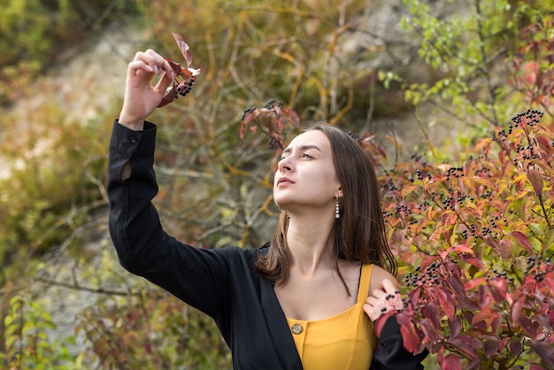 Porträt eines hübschen Modemädchens in der Nähe eines Herbstbuschs, genießen Sie die Natur