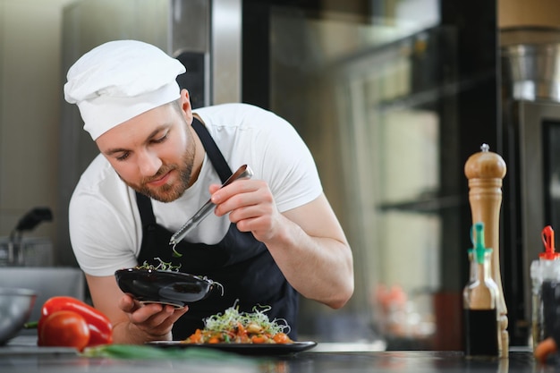 Porträt eines hübschen positiven Kochkochens in der Küche des Restaurants