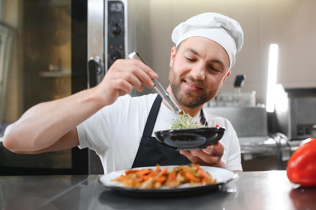 Porträt eines hübschen positiven Kochkochens in der Küche des Restaurants