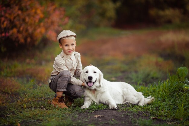 Porträt eines hübschen stilvollen Jungen in einer Kappe mit einem Haustier-Retriever