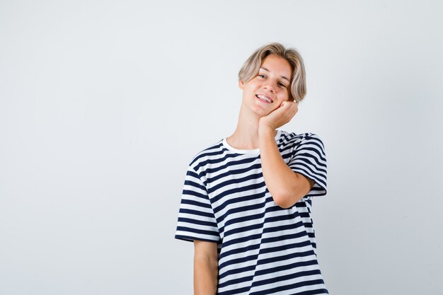 Porträt eines hübschen Teenagers, der sich in gestreiftem T-Shirt auf die Handfläche lehnt und fröhliche Vorderansicht sieht