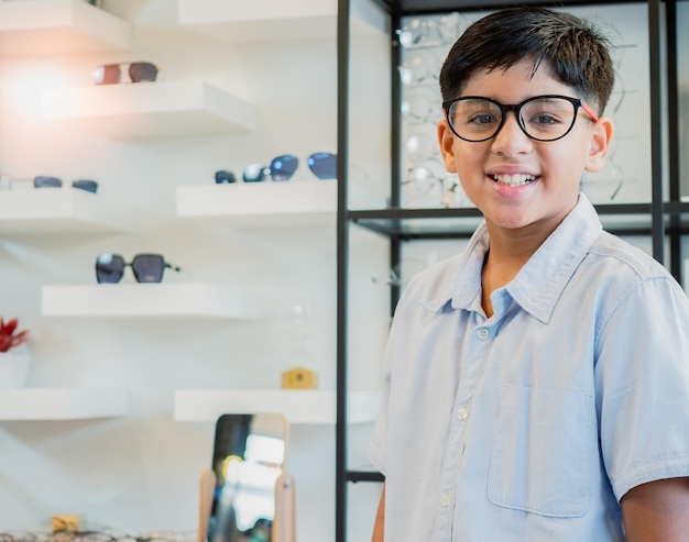 Porträt eines indischen Jungen, der eine Brille im Optikgeschäft auswählt