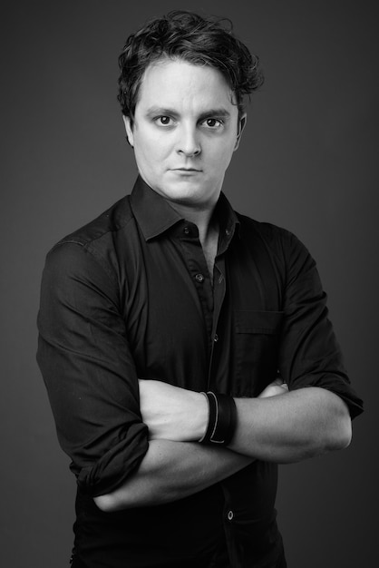 Porträt eines italienischen Geschäftsmannes, der ein schwarzes Hemd auf Grau in Schwarzweiß trägt