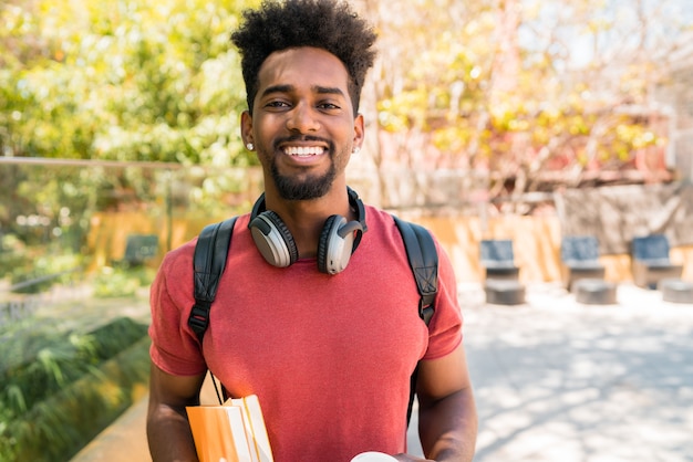 Porträt eines jungen Afro-Universitätsstudenten, der seine Bücher hält