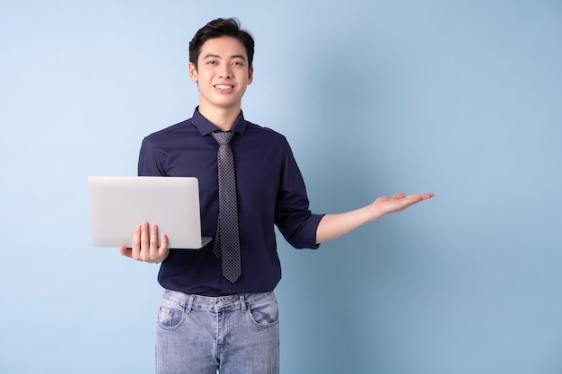 Porträt eines jungen asiatischen Geschäftsmannes mit Laptop auf blauem Hintergrund
