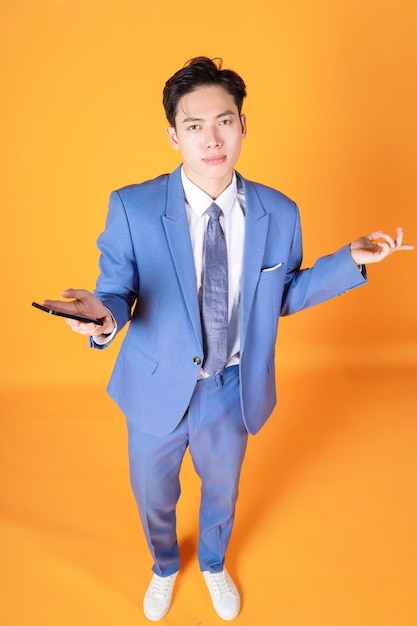 Porträt eines jungen asiatischen Geschäftsmannes mit Smartphone im Hintergrund