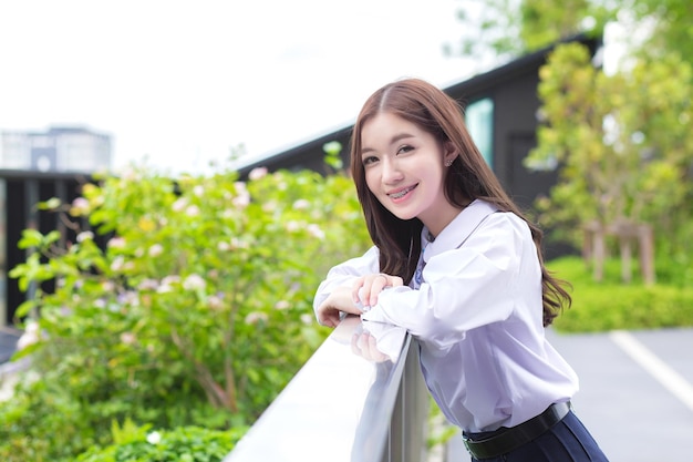 Porträt eines jungen asiatischen Mädchens in Schuluniform lächelt mit Zahnspangen in einem grünen Park