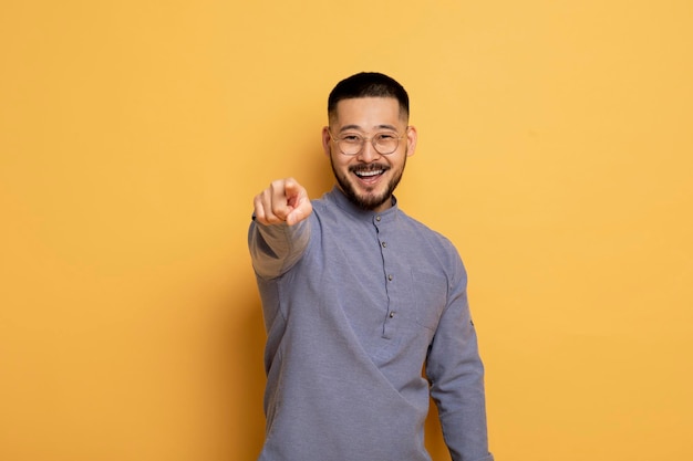 Porträt eines jungen asiatischen Mannes, der mit dem Zeigefinger auf die Kamera zeigt