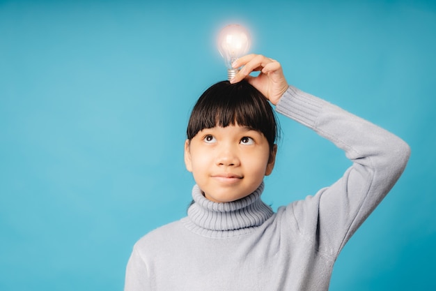 Porträt eines jungen asiatischen Studenten und Mädchens, die eine Glühbirne auf dem Kopf halten und denken, Idee und pädagogische Innovation des Kinderkonzepts