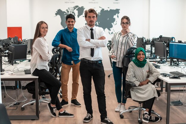 Porträt eines jungen aufgeregten multiethnischen Geschäftsteams von Softwareentwicklern, die im modernen Startup-Büro stehen und in die Kamera schauen. Hochwertiges Foto