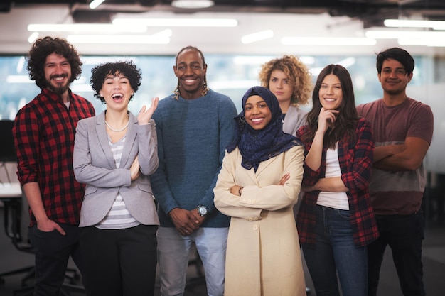 Foto porträt eines jungen aufgeregten multiethnischen geschäftsteams von softwareentwicklern, die stehen und in die kamera schauen, während sie den erfolg im modernen startup-büro feiern
