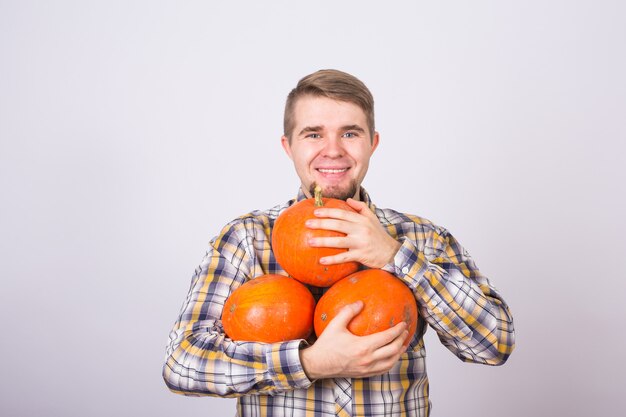 Porträt eines jungen Bauern, der Kürbisse auf einem hellen Hintergrundstudio hält