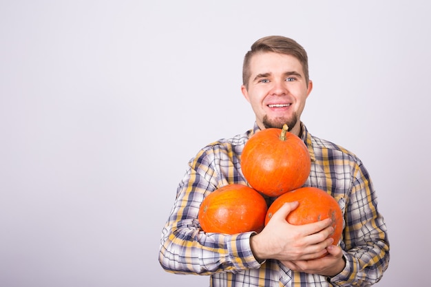 Porträt eines jungen Bauern, der Kürbisse auf einem hellen Hintergrundstudio hält