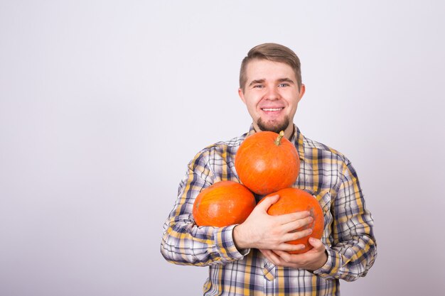 Porträt eines jungen Bauern, der Kürbisse auf einem hellen Hintergrundstudio hält