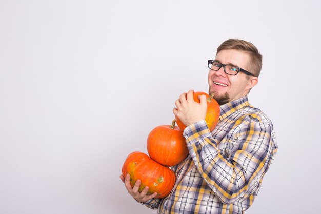 Porträt eines jungen Bauern, der Kürbisse auf einem hellen Hintergrundstudio hält