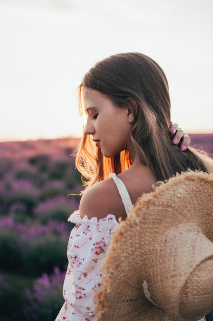 Porträt eines jungen blonden Mädchens in einem Lavendelfeld im Sommer bei Sonnenuntergang